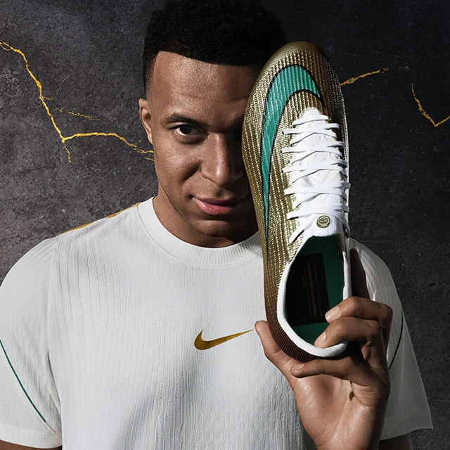 kylian mbappe holding a cleat.