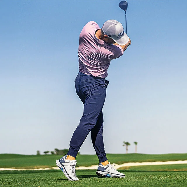 Golfer swinging on golf course.