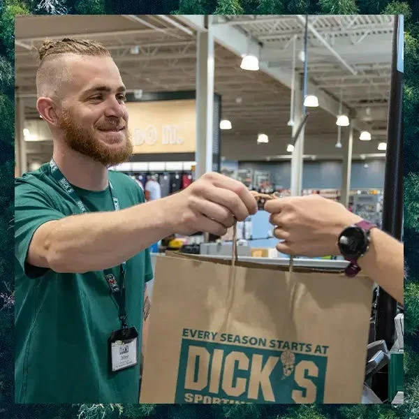 A teammate handing a shopping bag to athlete.