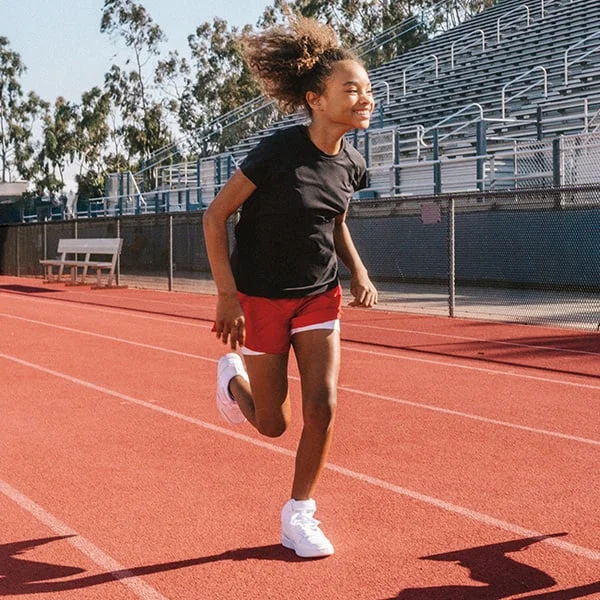Young girl running outside on a track. 