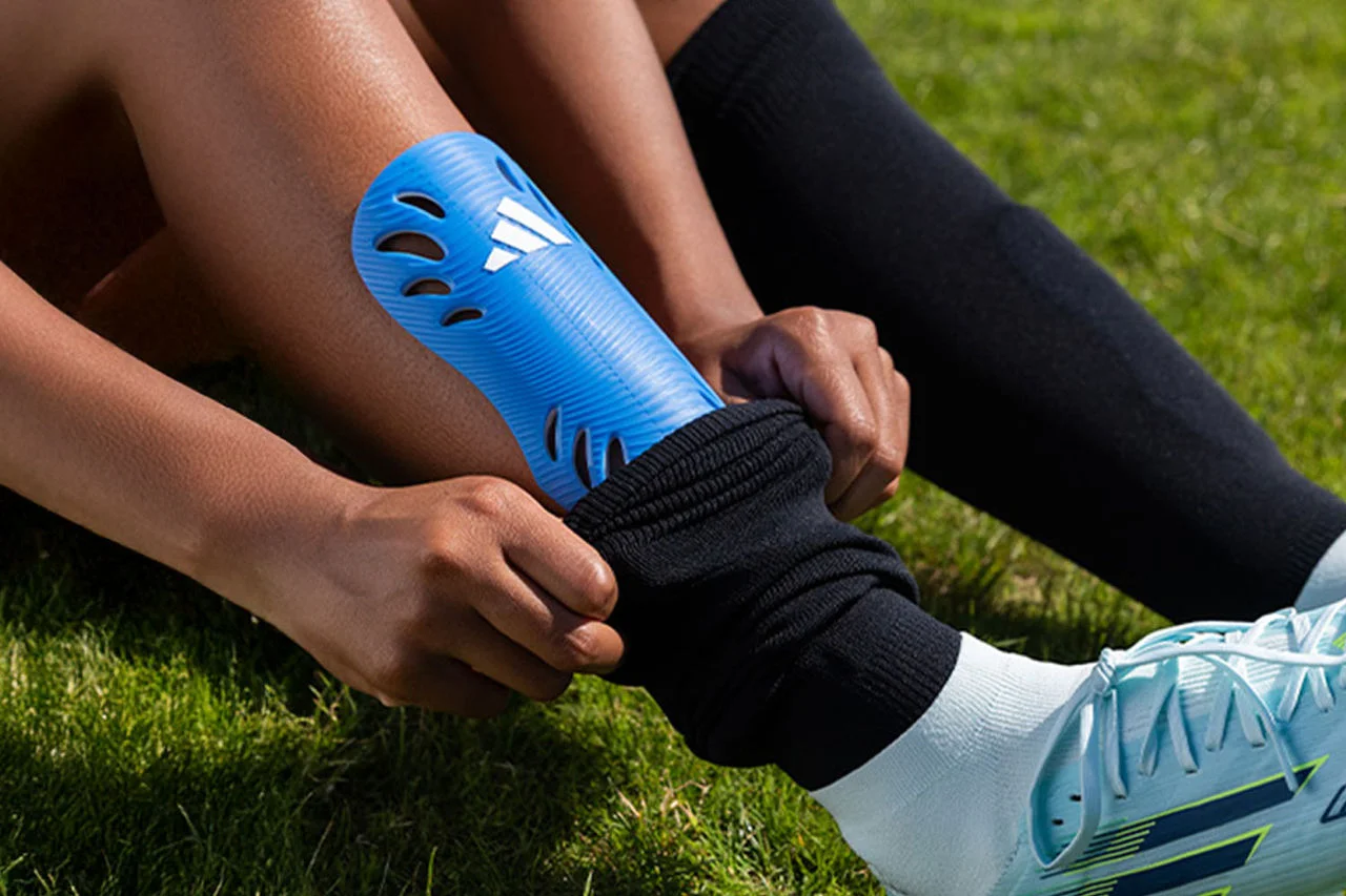 person pulling up sock over shin guard