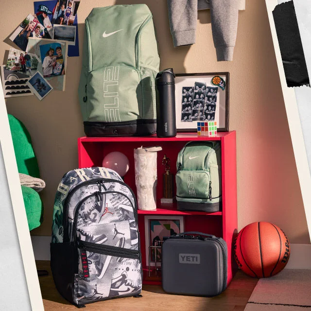 Water bottles and backpacks on a shelf in a dorm room.