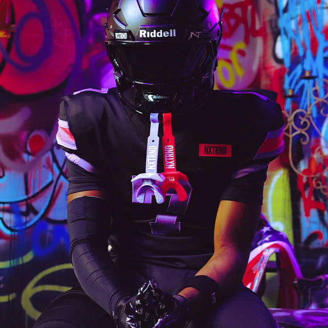 Football player wearing full game gear with mouthguards attached to helmet.