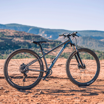 A man zipping down a desert hill on a Mongoose full-suspension mountain bicycle.