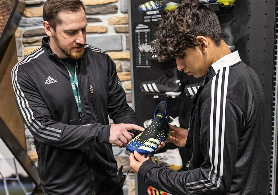 A store employee helping a customer shop for shoes