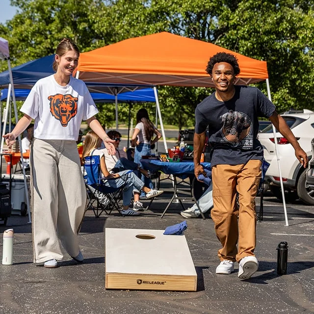 Friends playing cornhole at outdoor tailgate