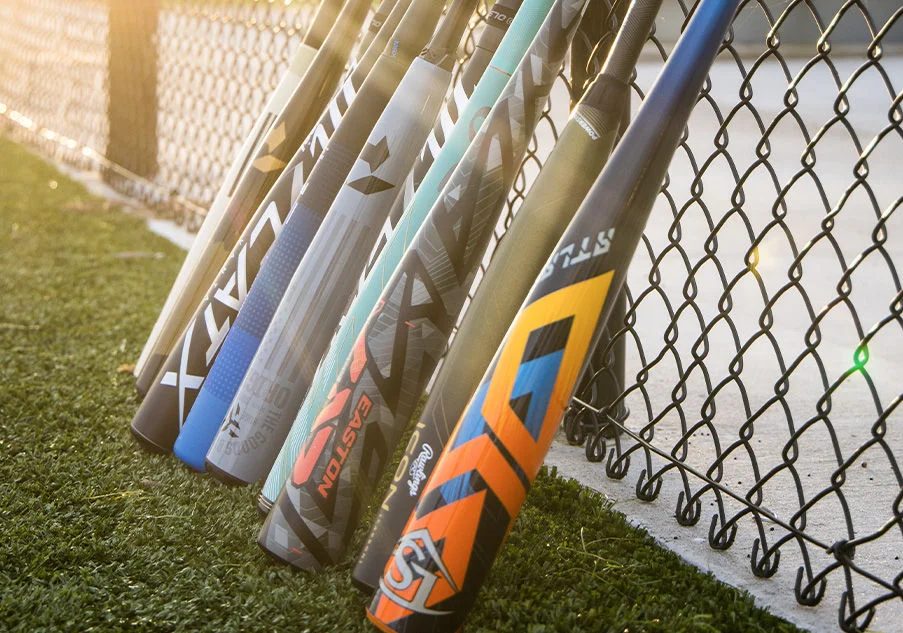 Baseball bats leaning against a fence.