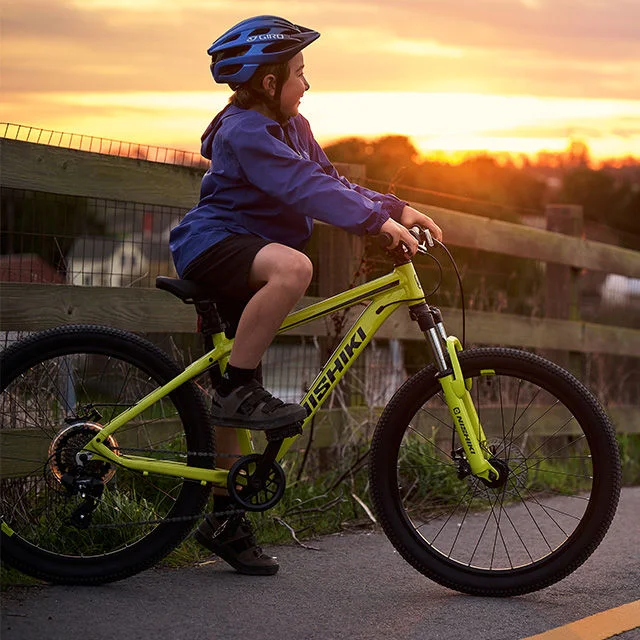 Child on bicycle with sunset in the distance.