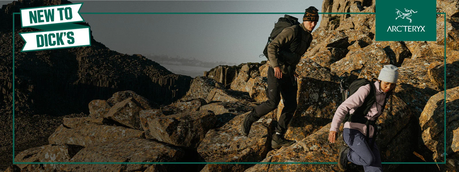 A couple climbing on a trail wearing athletic clothing.