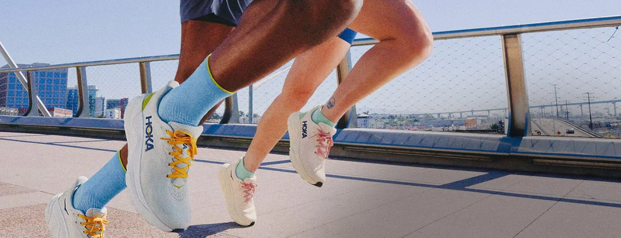 Two people running in HOKA running shoes. 