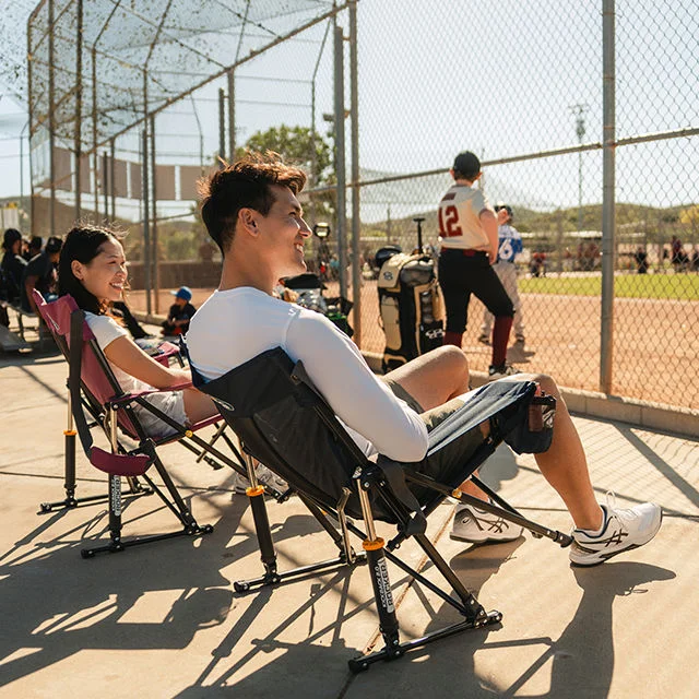 Athletes sitting in chairs watching a baseball game.