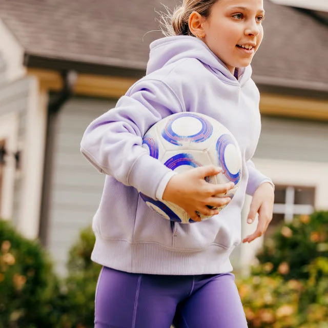 A girl running with a soccer ball.