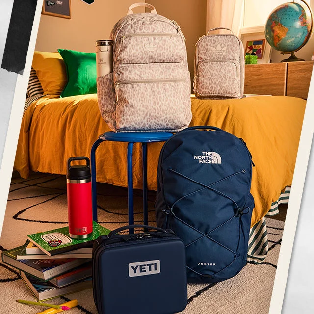 Water bottles and backpacks on a shelf in a dorm room.