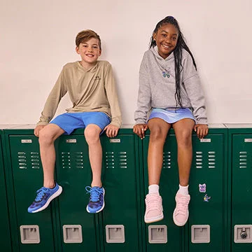 Two kids sitting on green lockers