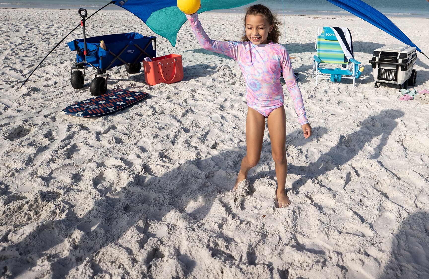 A young girl at the beach in swimwear.