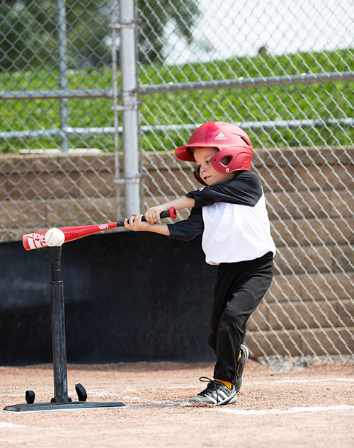 young boy swinging tee ball bat