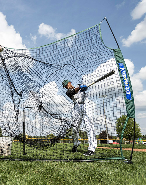 man swinging into baseball and softball batting net