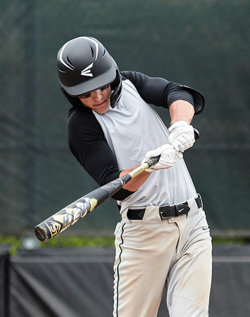 man swinging baseball bat on field
