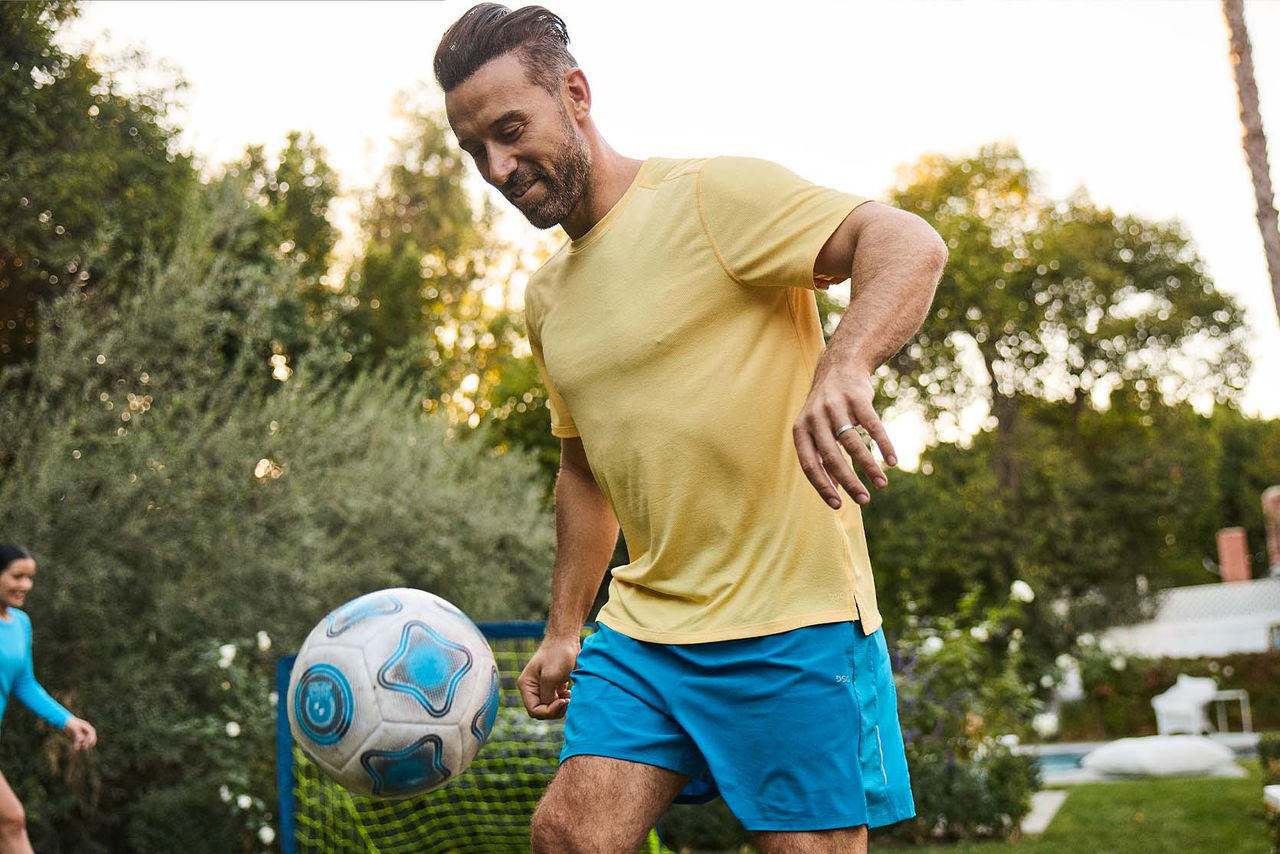 man playing soccer in back yard