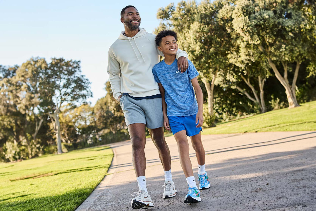 father and son walking outdoors on path smiling