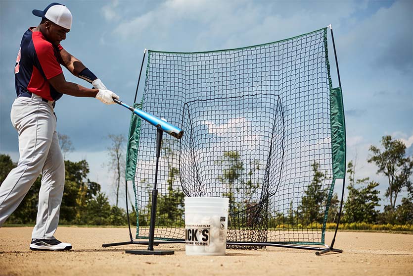 baseball player hitting ball off of tee