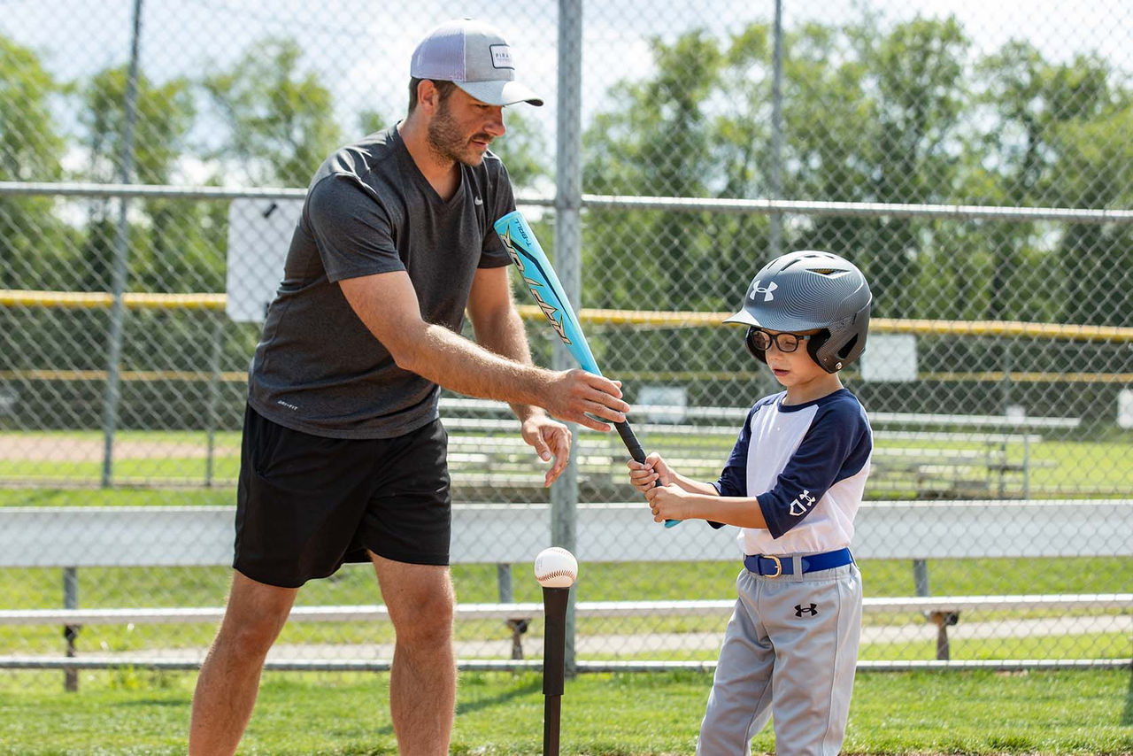 tee ball player and coach assisting