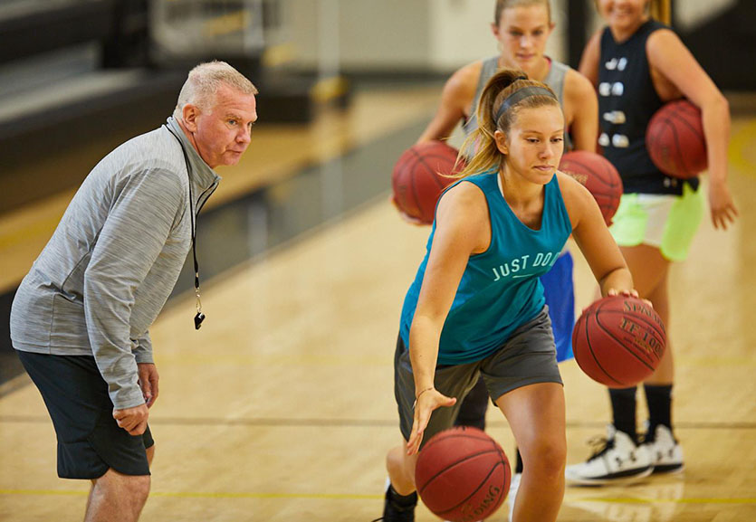 Female youth basketball players line up to complete drills for a tryout