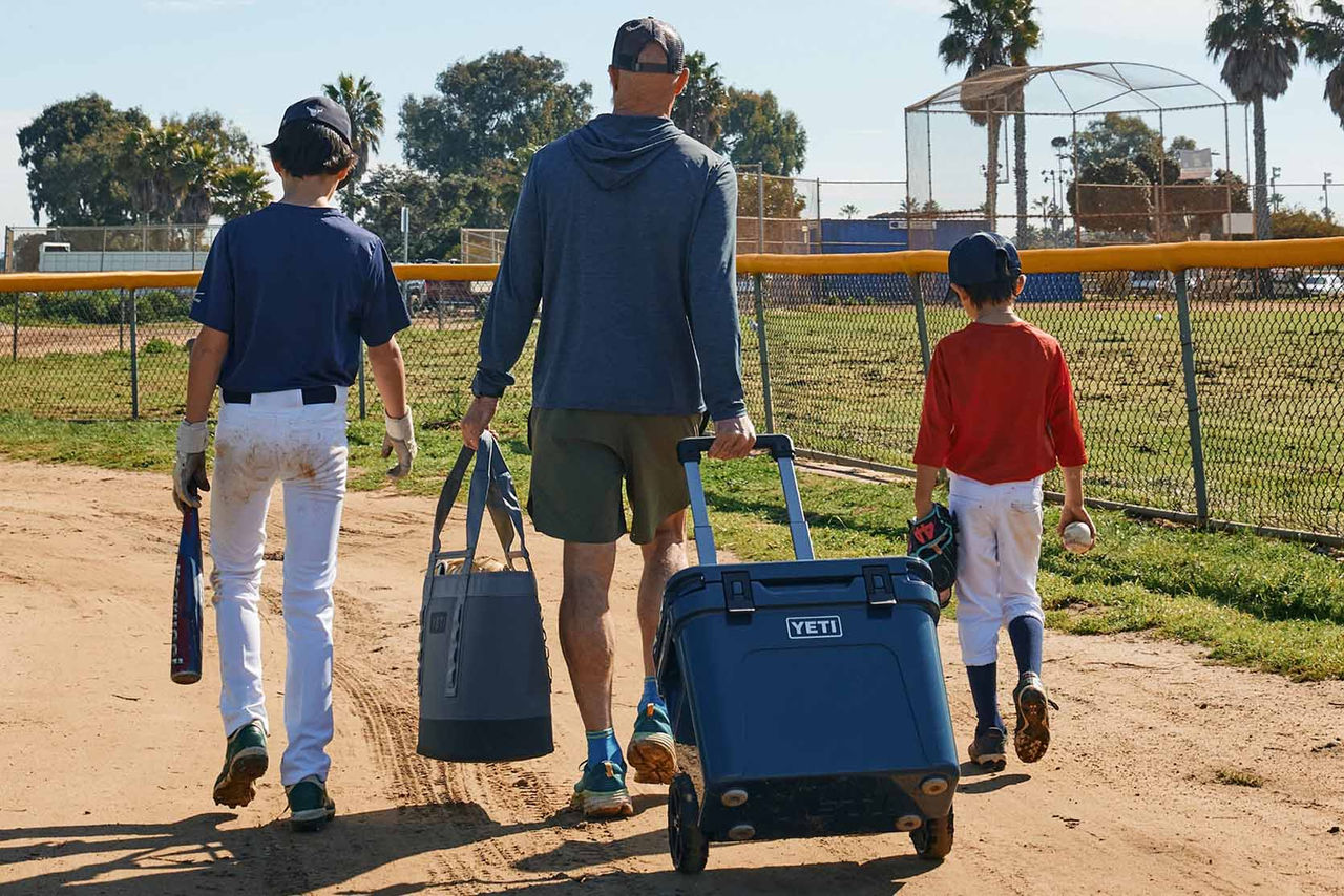family walking away from baseball field with Yeti cooler