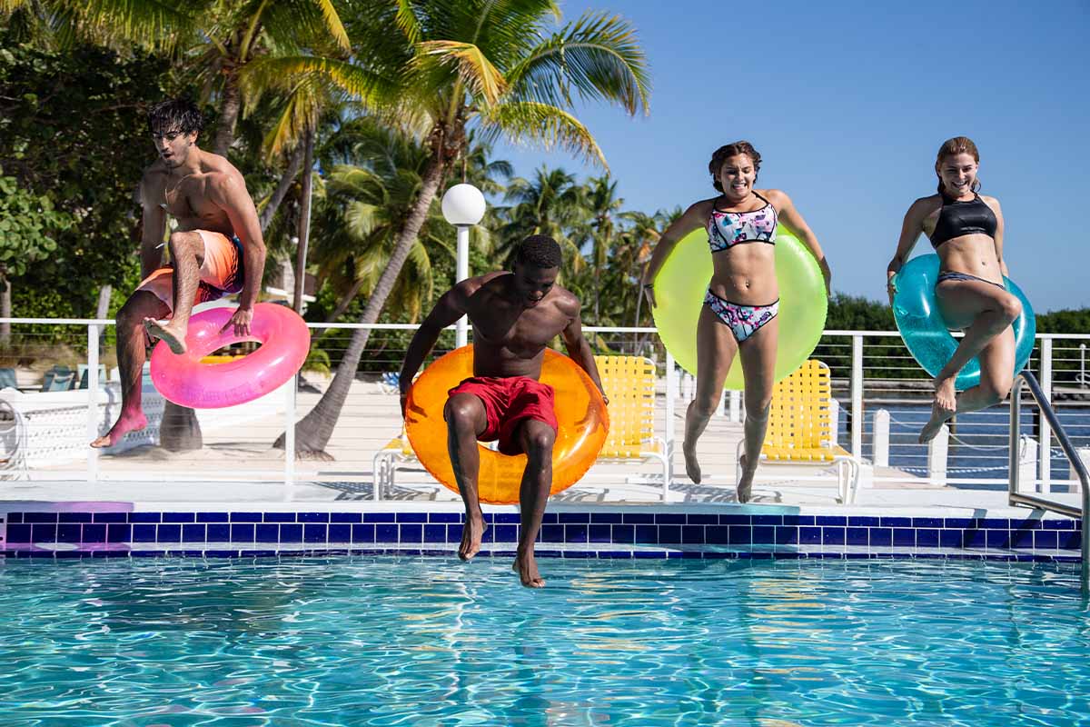 People jumping into a pool having fun.