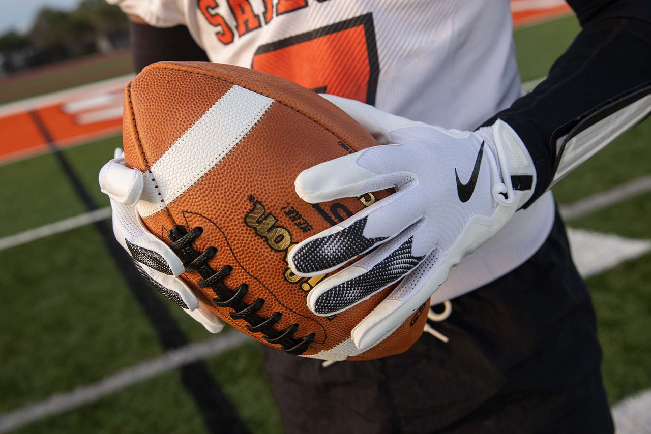 person holding football with gloves on