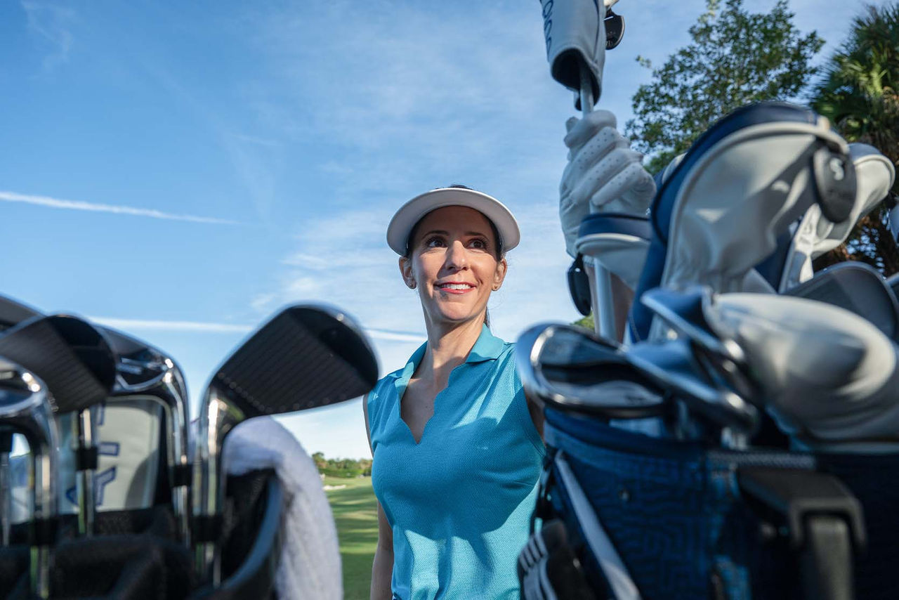 woman reaching in bag for clubs