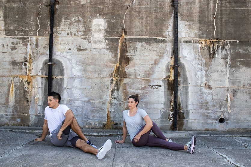 Man and Women sitting on the ground stretching. 