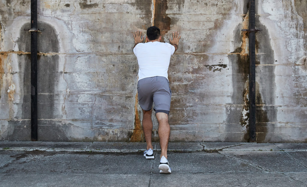 Man doing a wall calf stretch 