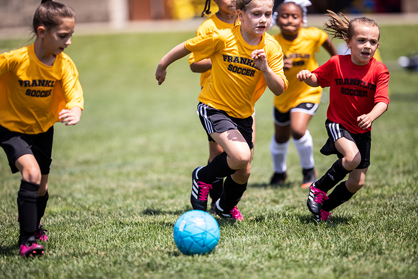 kids running to kick soccer ball with cleats