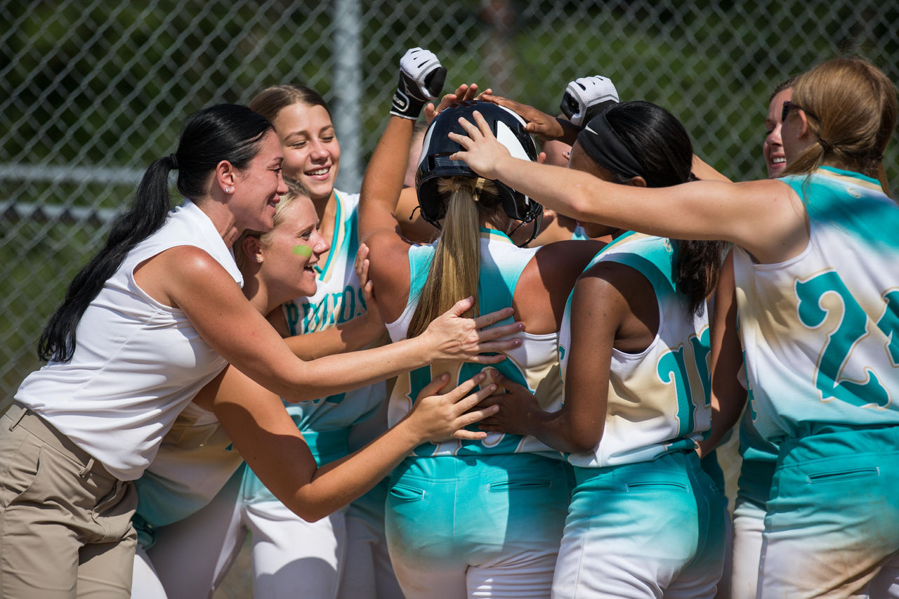 softball team celebrating with coach