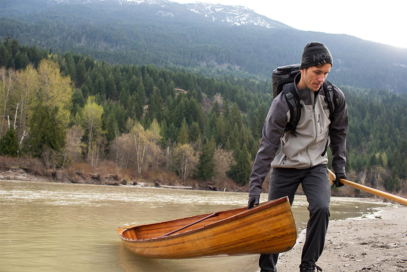 Man dragging a canoe out of the water.