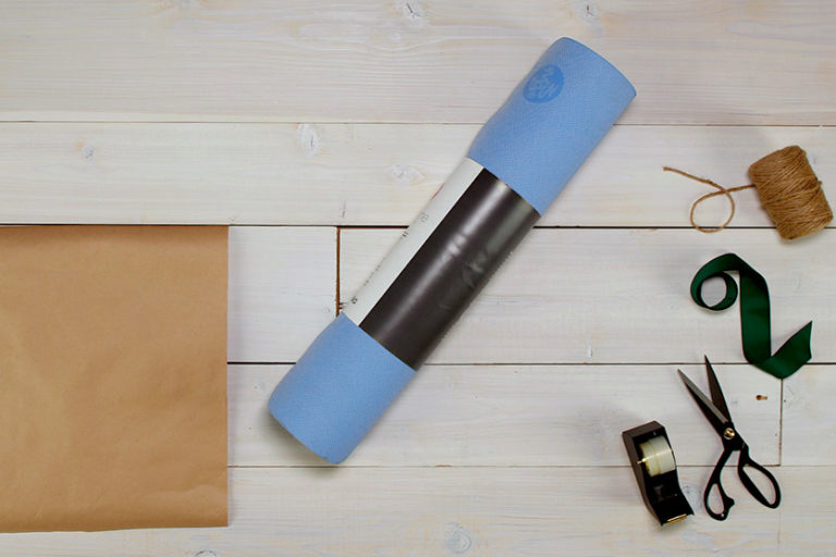 Rolled up yoga mat laying next to tissue wrapping paper